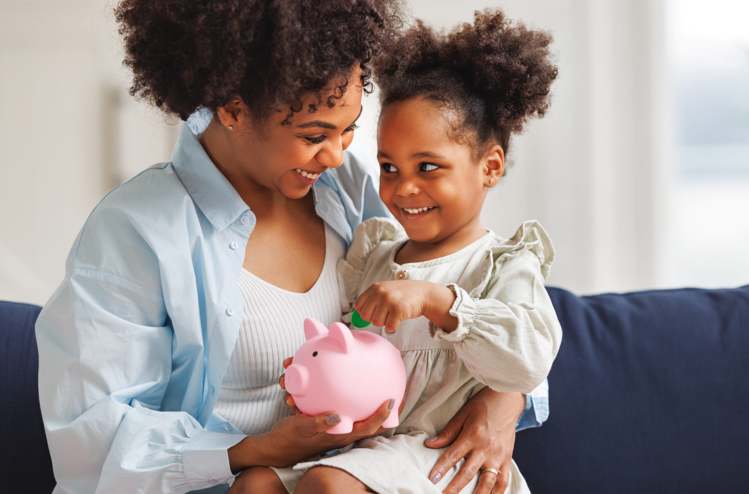 mom and daughter looking at piggy bank together